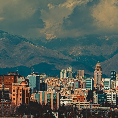 A cityscape of Tehran, dramatically framed by mountains.